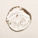 Gota de gel de ácido hialurónico sobre fundo bege, ilustrativa do tratamento com skinbooster