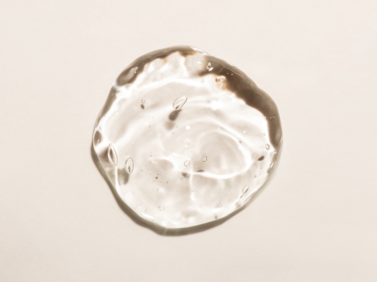 Gota de gel de ácido hialurónico sobre fundo bege, ilustrativa do tratamento com skinbooster